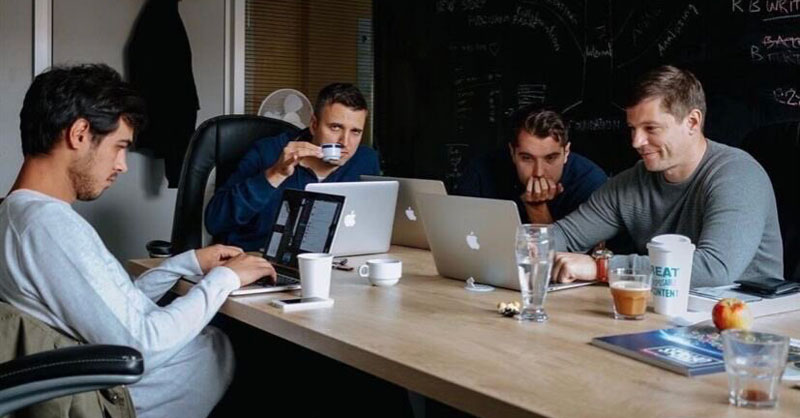 A group of programmers sitting around a table, working on their laptops